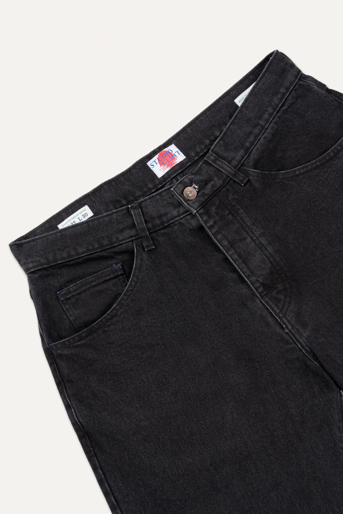 The back pocket detail of coal black denim jeans, showing the signature bartack stitching.