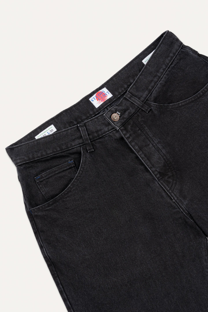 The back pocket detail of coal black denim jeans, showing the signature bartack stitching.