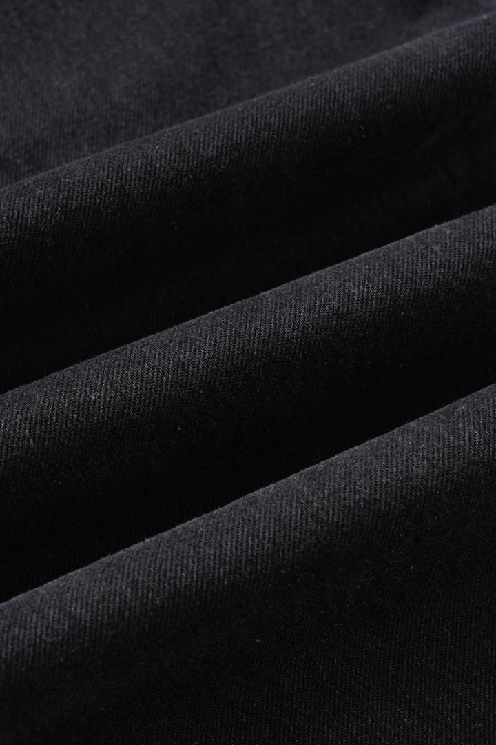 A close-up of the front pockets and belt loops on coal black denim jeans.