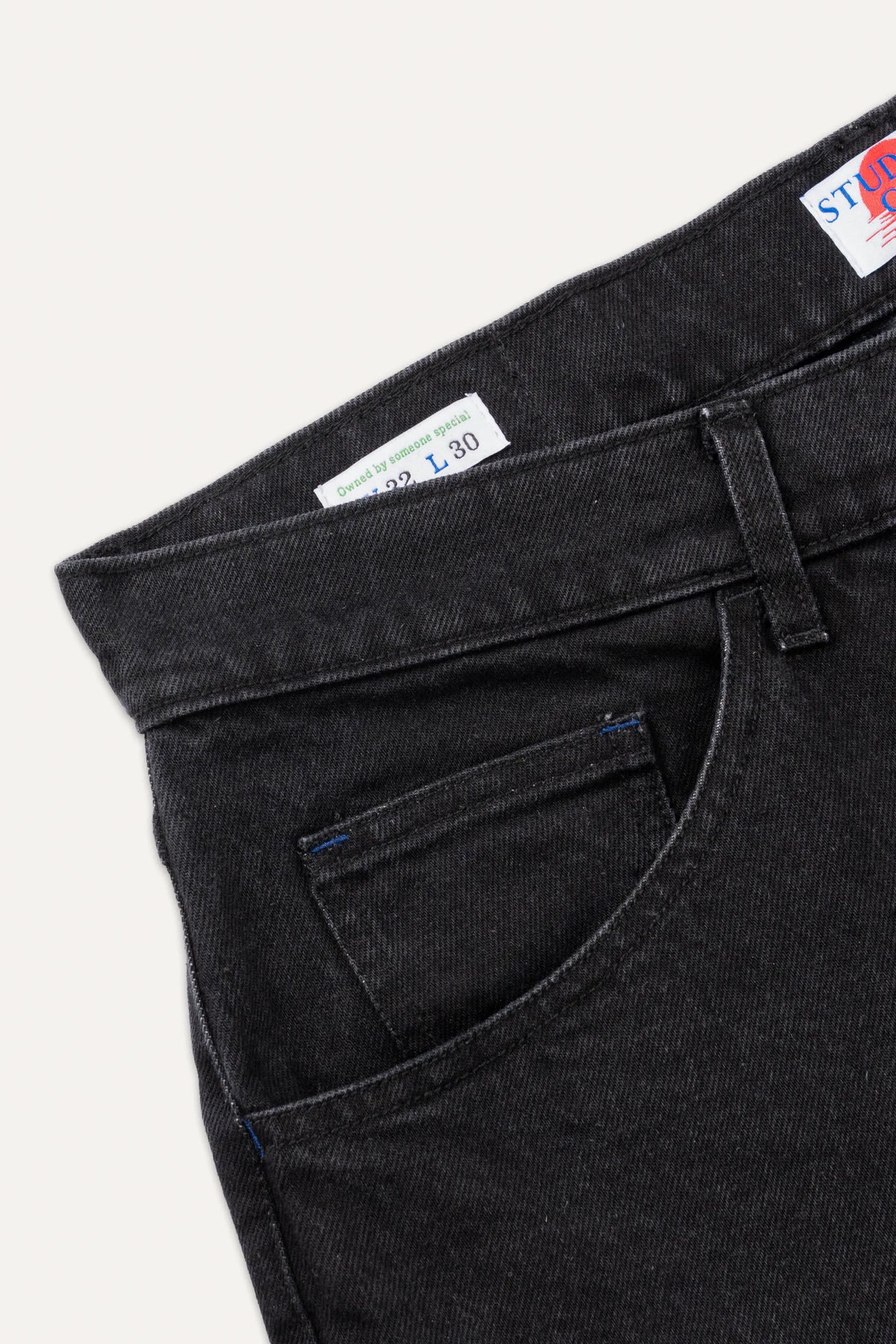 A close-up of the rear waistband and belt loops on coal black denim jeans.
