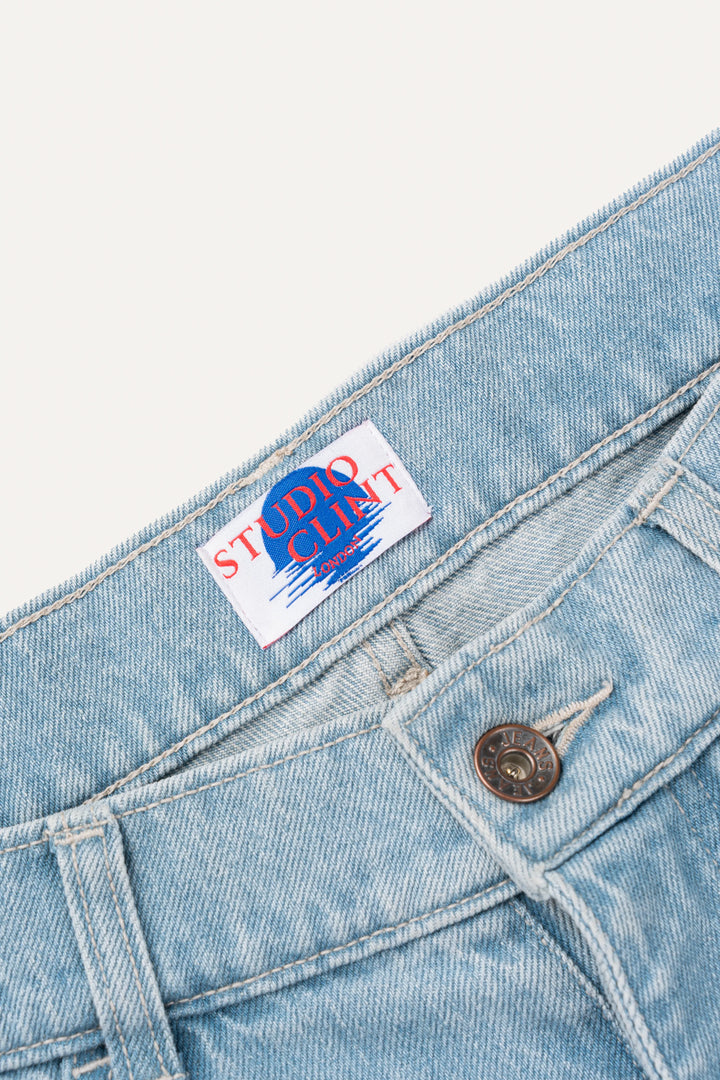 The back pocket detail of light blue denim jeans, showing the signature bartack stitching.