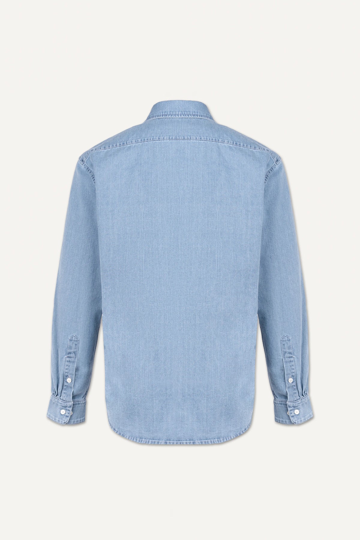 A light blue denim long-sleeve shirt shown from the back, featuring a button-down cuff and a curved hem, photographed against a solid off-white background.