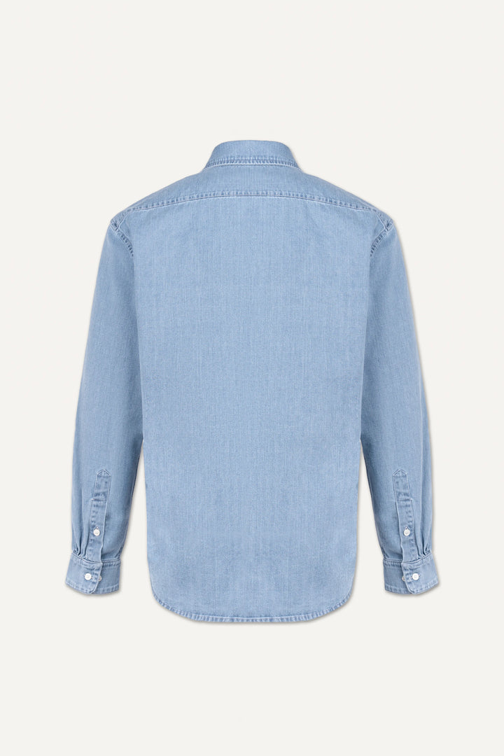 A light blue denim long-sleeve shirt shown from the back, featuring a button-down cuff and a curved hem, photographed against a solid off-white background.