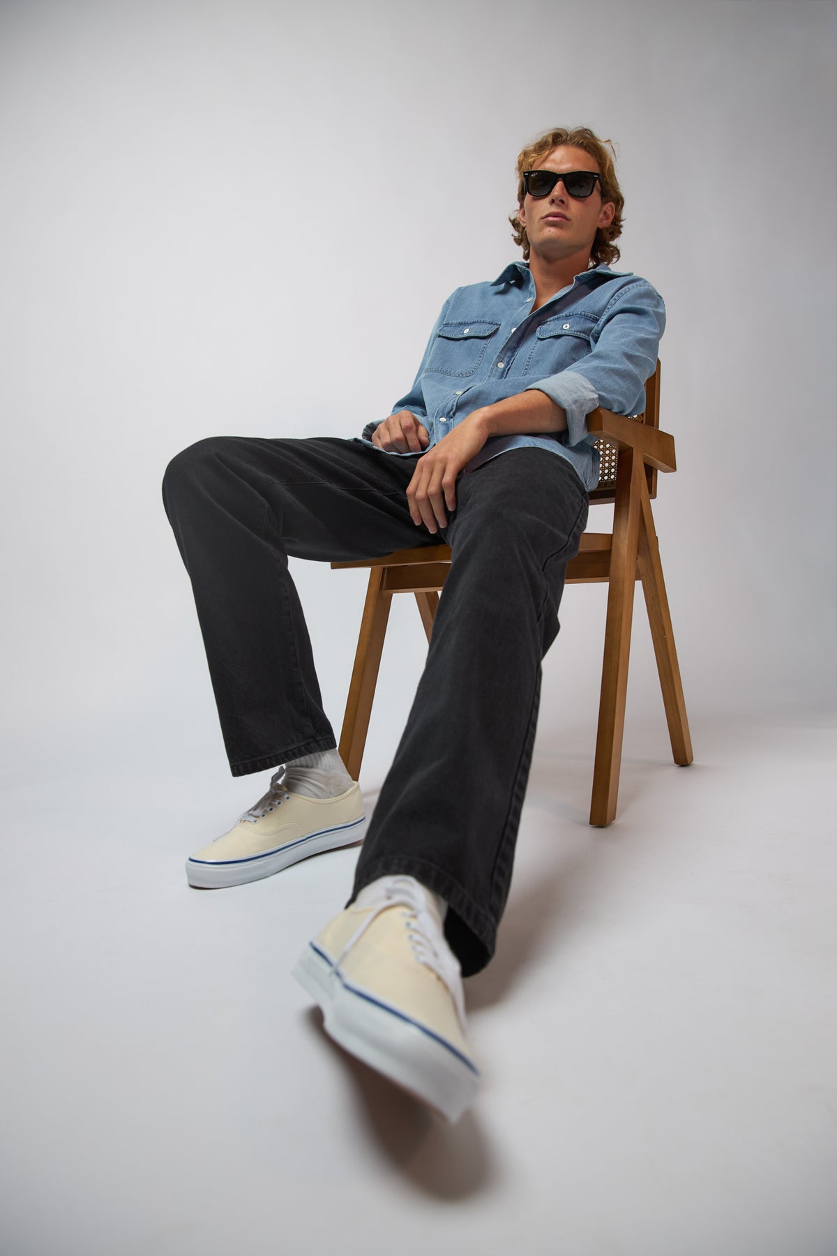A man wearing coal black denim jeans with a navy jacket, standing against a plain grey studio background.
