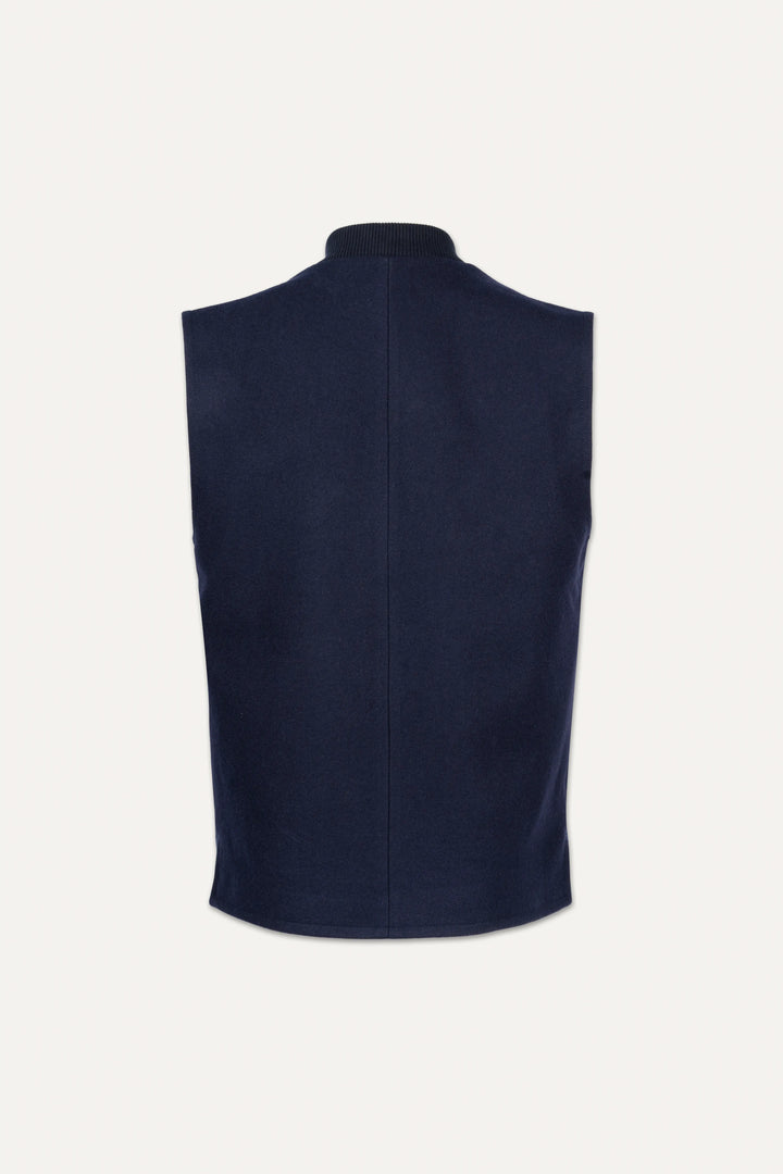 A sleeveless navy blue knit vest shown from the back, featuring a high folded collar and a central seam, set against a plain off-white background.